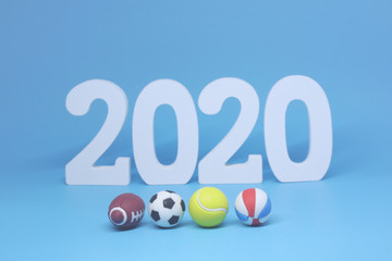 White Wooden 2020 with Football Tennis ball Volleyball Rugby on blue  background - 2020 sport and activity concept - New Challenge and New Goal for the Winner 