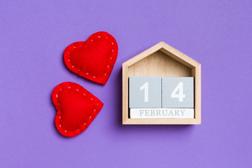 Top view of wooden calendar and textile hearts on colorful background. The fourteenth of February. Valentine's day concept