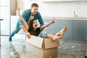 young couple husband and wife looking happy having fun while unpacking and moving in new...