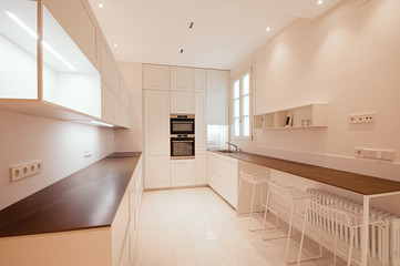 Classic modern kitchen with wooden and white details, minimalistic interior design, modern furniture whith lifting systems. Kitchen with integrated appliances.