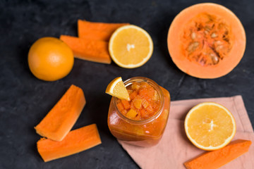 Fototapeta na wymiar pumpkin and orange jam in a glass jar on a dark background. . orange halves on the background of a jar of jam