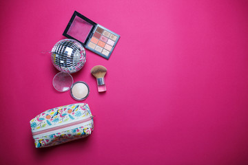 Cosmetics on pink background. Colorful image for cosmetics theme. Powder, highlighter, brush, eyeshadows and cosmetic bag on pink background.