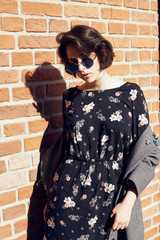 Summer sunny lifestyle fashion portrait of young stylish hipster woman walking on the street