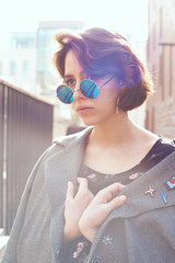 Summer sunny lifestyle fashion portrait of young stylish hipster woman walking on the street