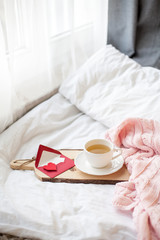 Fototapeta na wymiar Beautiful white cup with tea on the bed, pink knitted plaid, postcard Happy Valentine's Day. Breakfast in bed. Morning. Spring. Cozy.