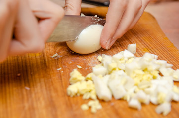 female hands cut eggs on a wooden Board close up