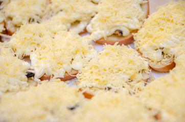 sandwiches with sprats, mayonnaise and frayed cheese on a plate close-up