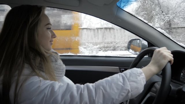 Young blond girl is driving car. Winter