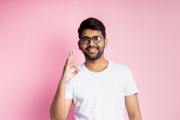 Portrait of handsome Indian guy standing on pink background