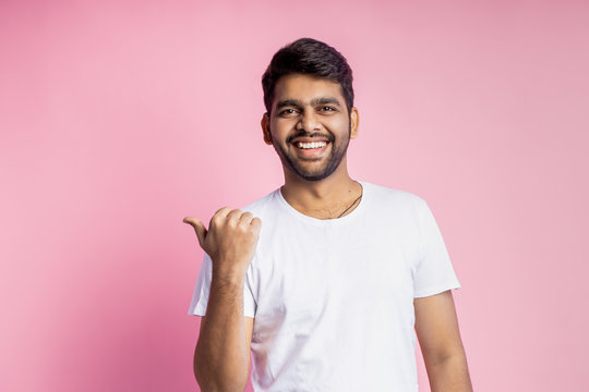 Portrait of handsome Indian guy standing on pink background