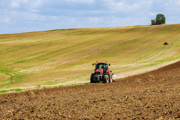Obraz premium Farmer on a tractor plows the land before sowing with a seedbed cultivator