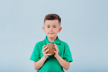 boy with coconut in hand. isolated on blue background, copy space, in studio, - obrazy, fototapety, plakaty