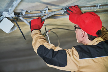 electrician service. Installer works with cable on ceiling