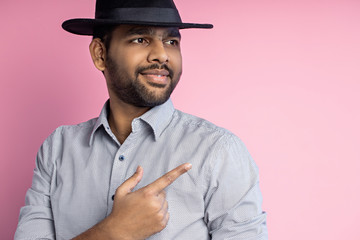 Portrait of handsome Indian guy standing on pink background