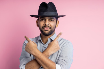 Portrait of handsome Indian guy standing on pink background