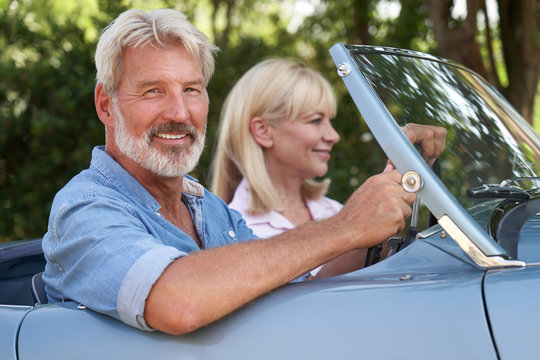 Mature Couple Enjoying Road Trip In Classic Open Top Sports Car Together