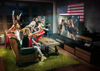 Group of friends watching TV, martial arts, leisure activity. Emotional men and women cheering for favourite team, look on fighting for ball. Concept of friendship, sport, competition, emotions.