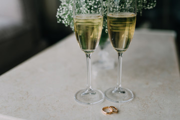 two glasses of champagne on table with wedding rings
