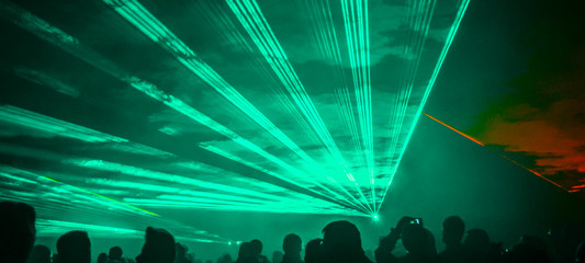  colorful outdoor laser show with silhouette of people