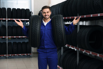 Male mechanic with car tires in auto store