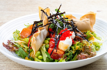 Salmon salad with cream cheese, pickled pumpkin, daikon, beans, tobiko caviar and mango chili sauce. Pan-Asian dish.