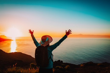 happy young woman hiking in sunset mountains near sea