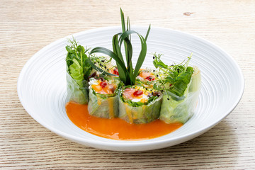 Salmon roll with Philadelphia cheese and pickled pumpkin, in rice paper with daikon and Ponzu sauce. Pan-Asian dish.