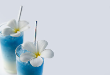 Iced blue butterfly pea latte drinks with tropical flowers decor. Healthy thai traditional cocktails in glasses