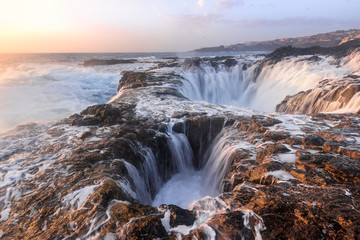 Olas batiendo en dos agujeros formados en las rocas al amanecer. Impresionante formación rocosa en Gran Canaria