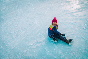 happy little girl learn to skate, child fall on ice, seasonal sport