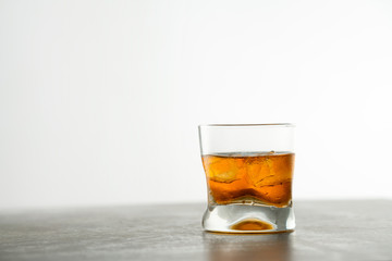 Glass of aged golden whiskey with ice cubes on the table. Amber colored alcohol beverage with rocks at the bar