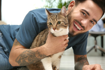Happy man with cat on floor at home. Friendly pet