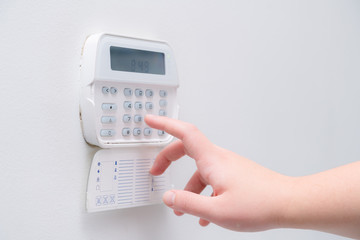 Woman hand entering alarm system password of an apartment, house of business office. Surveillance and protection console against rubbery and thief
