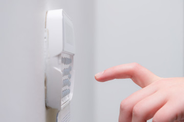 Woman hand entering alarm system password of an apartment, house of business office. Surveillance and protection console against rubbery and thief