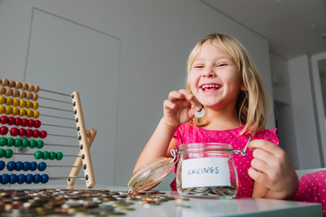 happy girl counting money, child put coins into saving jar