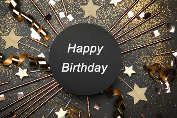 Flat lay composition with party decor and text Happy Birthday on black background
