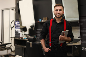 Fototapeta na wymiar Young business owner with tablet in barber shop