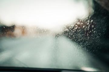 Bokeh defocused rain drops on windshield and car wipers are removing rain. Driving on rainy highway. 