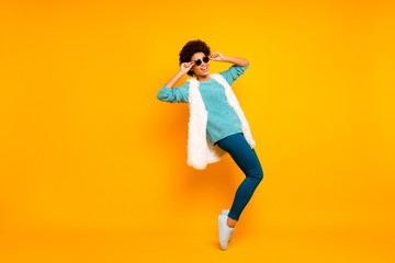 Fototapeta na wymiar Full size photo of cheerful afro american girl feel crazy dance dancer on night club clubber touch sunglass wear blue white teal pullover trousers isolated yellow color background