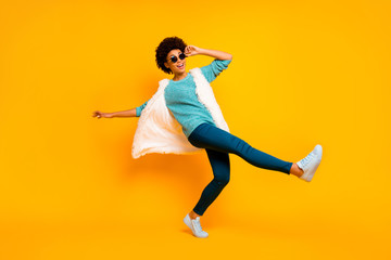 Fototapeta na wymiar Full size photo of funky afro american girl cool clubber dancer touch sunglass enjoy event dance raise legs wear turquoise stylish trendy white blue pants sneakers isolated bright color background