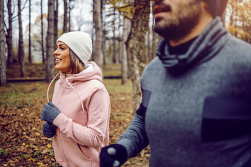 Fototapeta premium Dedicated young sporty couple in sportswear running in nature side by side on cold weather. Healthy lifestyle concept.