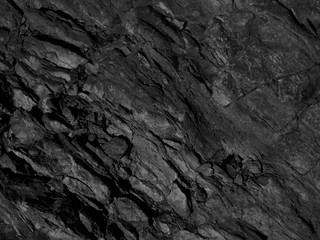 Black mountain texture. Close-up. Dark gray grunge background. Stone background. Black and white background. Monochrome rock texture.