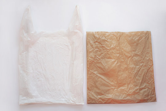 Blank plastic bag vs brown recyclable paper pack. Say no to plastic. Reduce, reuse and recycle concept. Eco friendly kraft bag and ugly synthetic packet, ecology problem. Flat lay on white background.