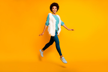 Fototapeta na wymiar Full size photo of cheerful afro american girl jump rest relax go walk feel dreamy emotions wear blue pants trousers teal pullover stylish trendy sneakers isolated over shine color background