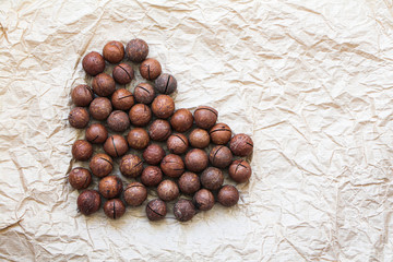 Heart shaped macadamia nuts on baking paper background. Healthy food concept