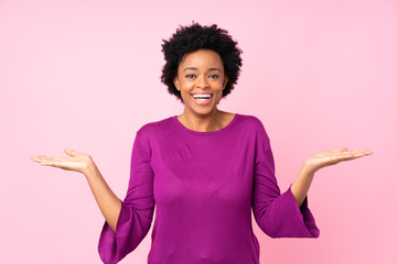 African american woman over isolated pink background with shocked facial expression
