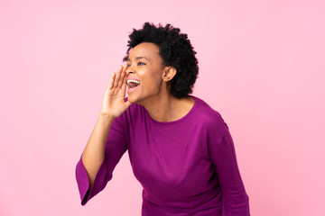 African american woman over isolated pink background shouting with mouth wide open to the lateral