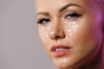 Fototapeta premium Portrait of gorgeous young half-naked bald woman with glitter face