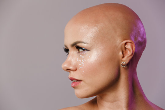 Portrait of gorgeous young half-naked bald woman with glitter face