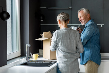 smiling man and woman unpacking box in new house